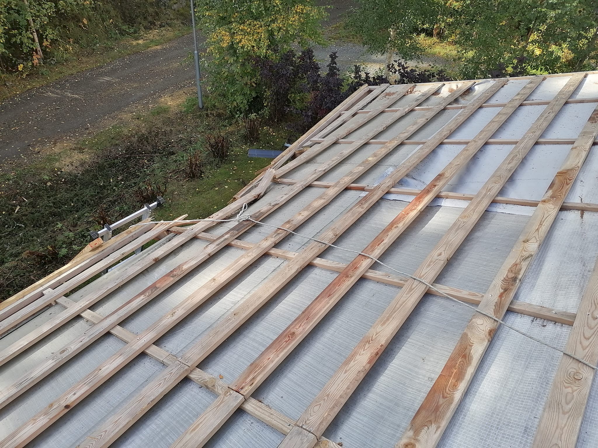 Katto on rakenteilla, puurimoja ja harmaa aluskate näkyvissä, ulkona.