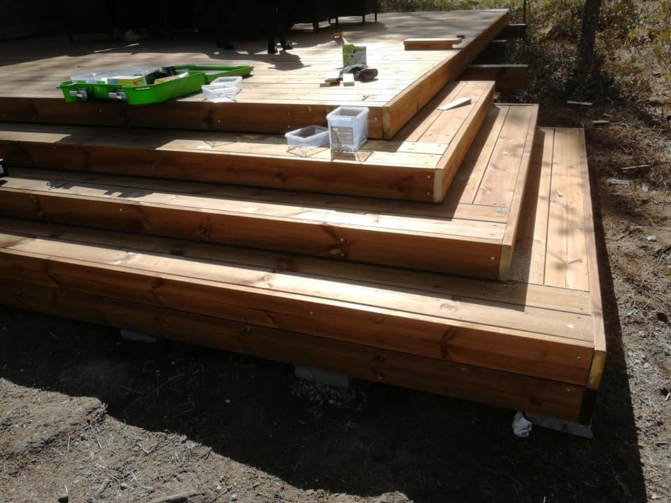 Puinen ulkoportaikko johtaa terassille, jossa on vihreä työkalupakki ja muita tarvikkeita.