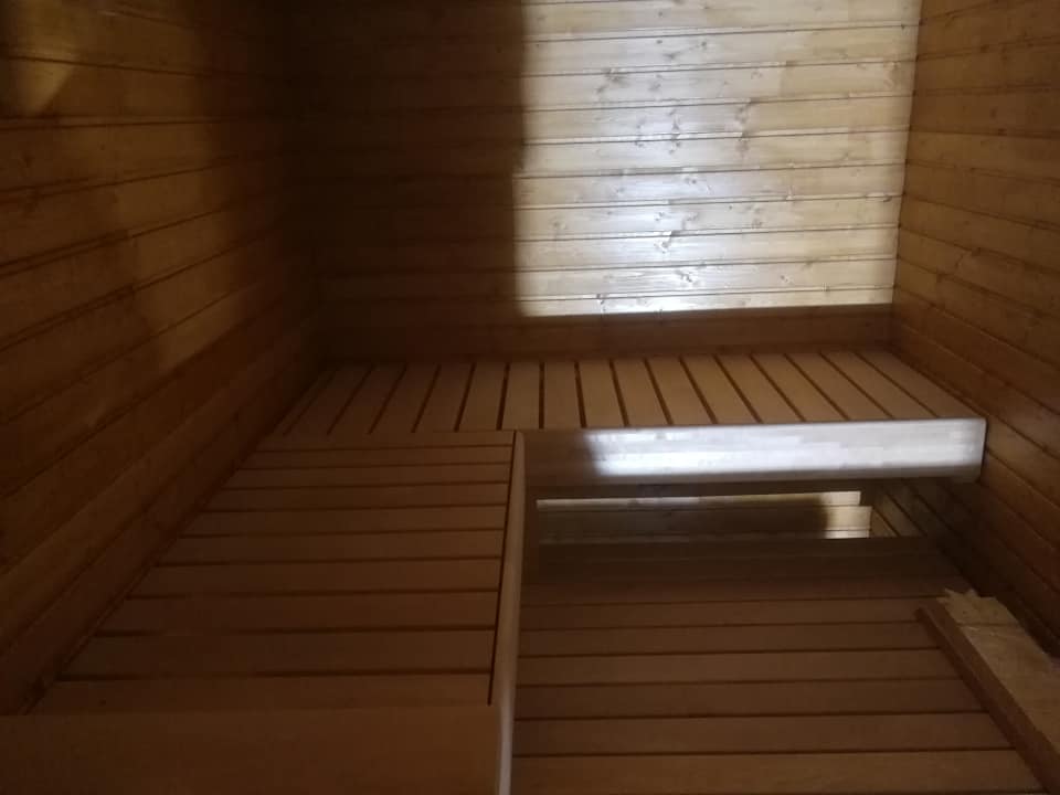 Puinen sauna, jossa on penkit ja seinät vaaleaa puuta, valaistus on lämmin.