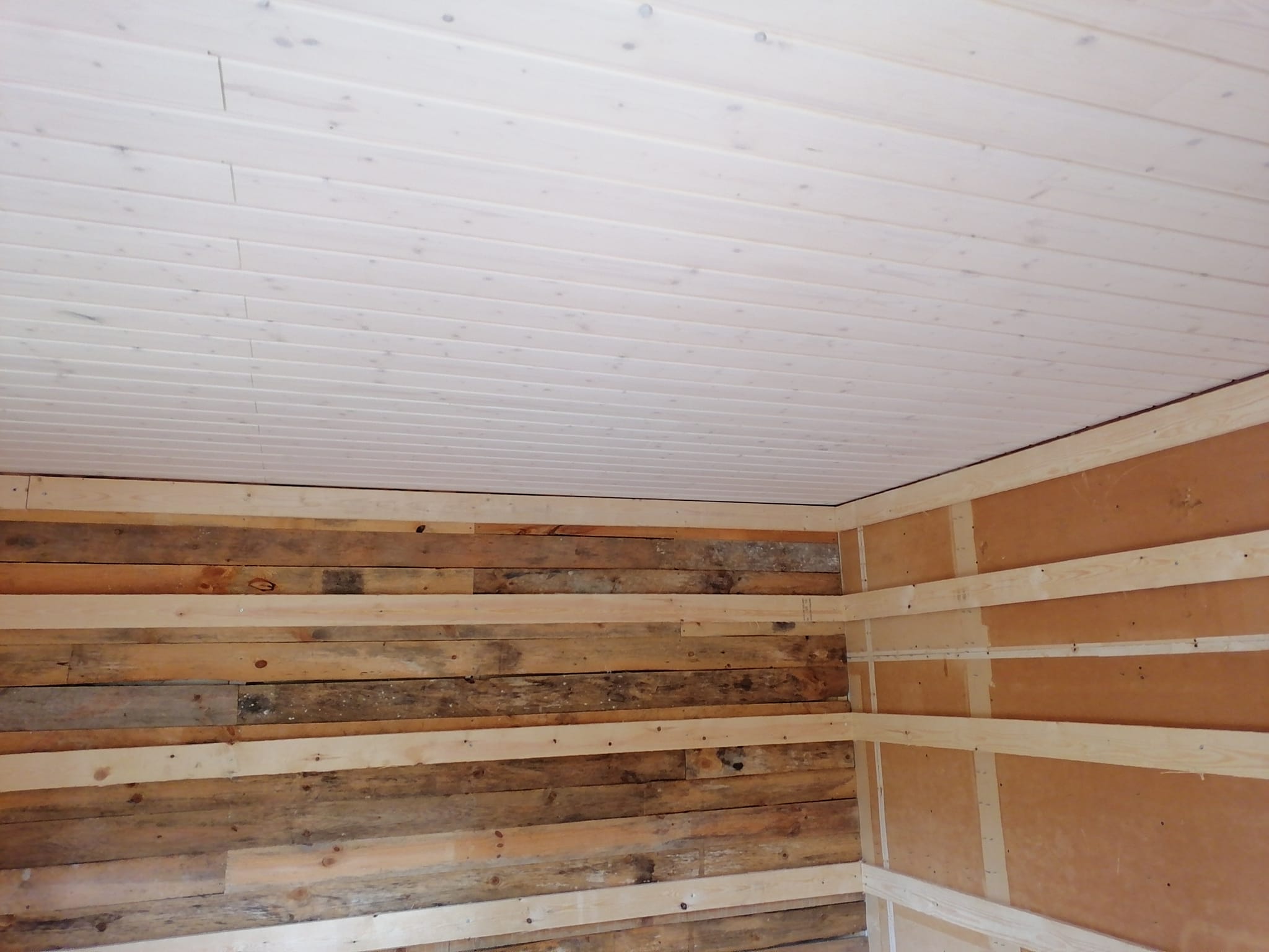 Puinen sisätila, jossa valkoinen paneelikatto ja puuseinät, joissa on ruskeita ja vaaleita sävyjä.