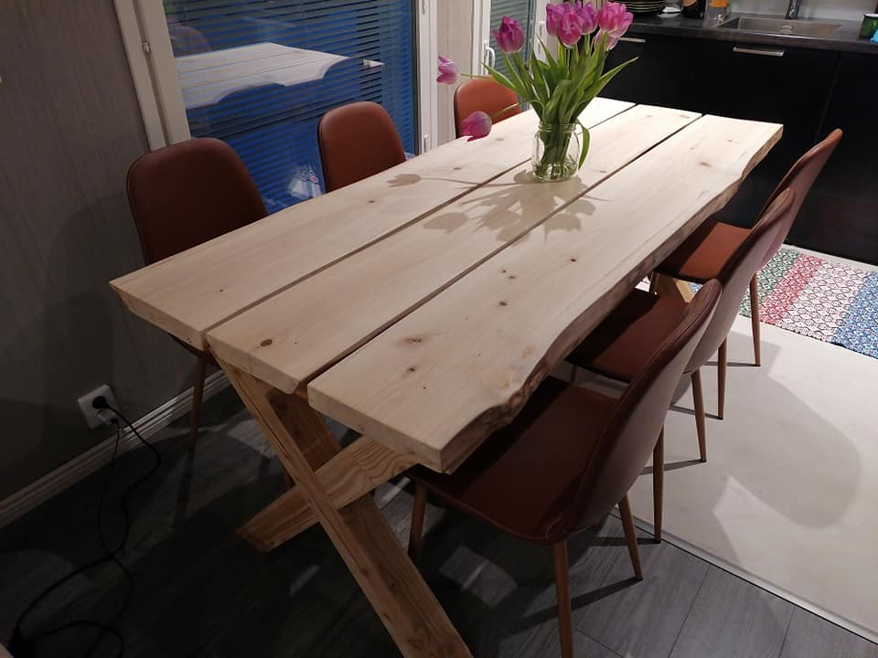 Ruokapöytä puusta, jossa on neljä ruskeaa tuolia ja maljakko tulppaaneja.