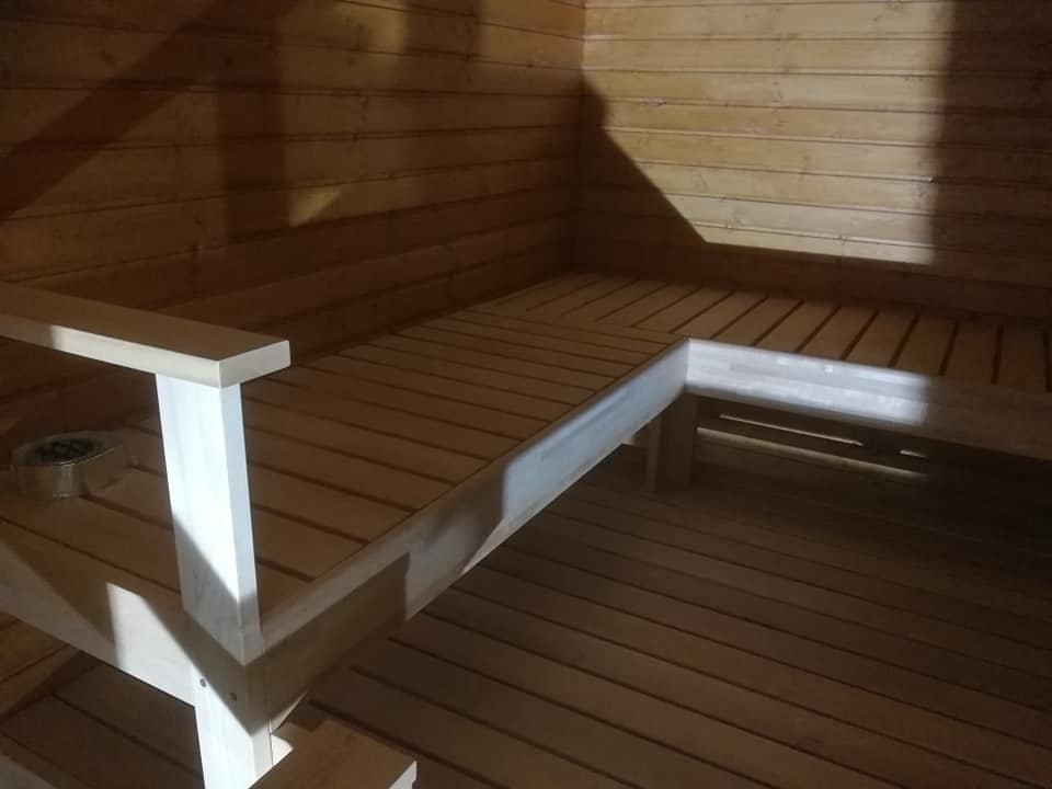 Kuvassa on puinen sauna, jossa on penkit ja seinät vaaleaa puuta. Valoisa ja lämmin tunnelma.