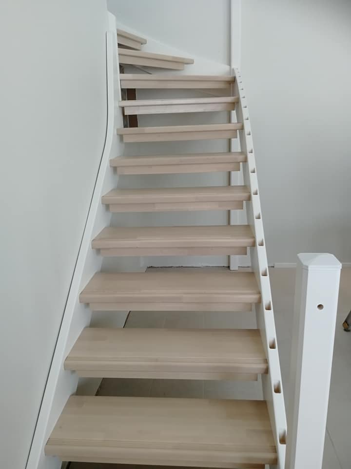 Vaaleat puuportaat valkoisella rungolla, valaistus on kirkas ja tasainen.