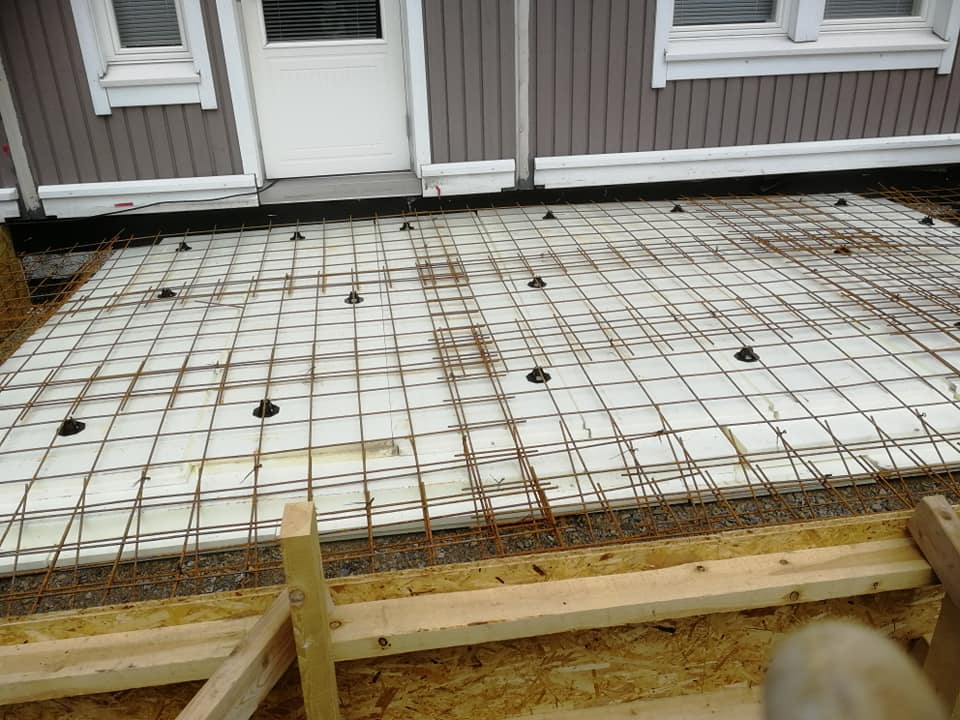 Rakennustyömaa, jossa on valkoinen eristys, teräsverkko ja puinen kehys, valoisa ja ulkona.