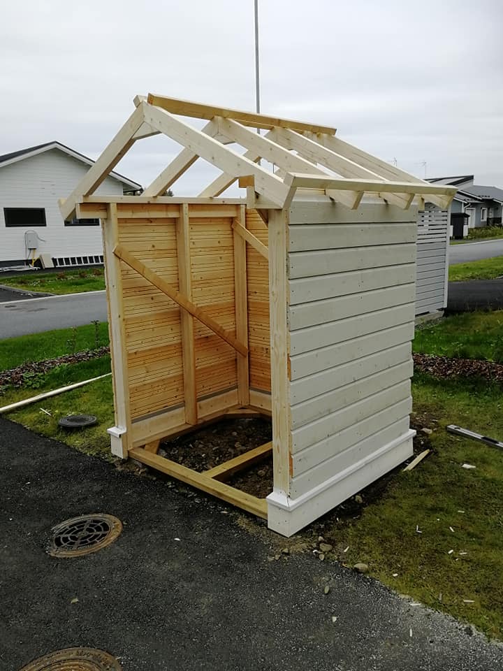 Puurakenteinen vaja rakenteilla, jossa on puinen runko, valkoiseksi maalattu ulkoverhous ja avoin katto.